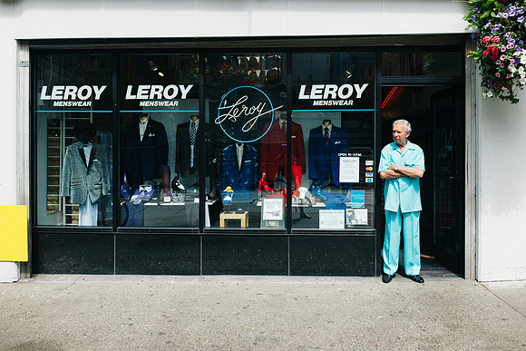 The proprietor of Leroy Menswear stand in the doorway and looks