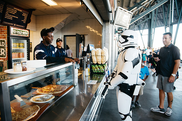 A First Order Stormtrooper orders a beer at the concession stand